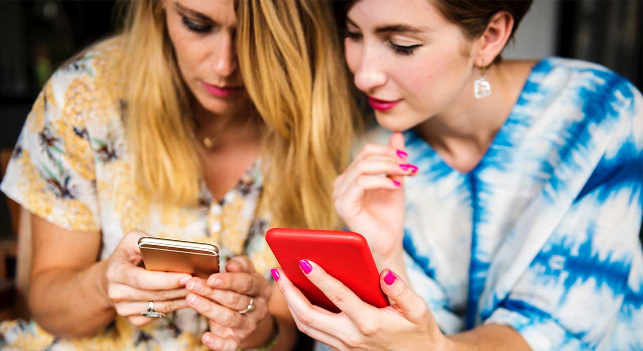 Duas mulheres a olhar para os seus telemóveis representam a melhoria da experiência do utilizador